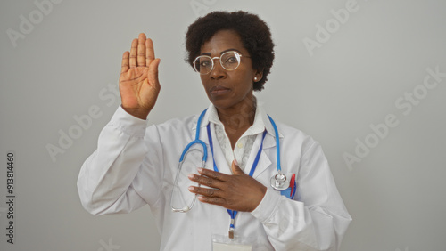 Photos Female doctor standing against a white background with her hand raised, taking a