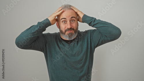Obraz na płótnie A perplexed caucasian man with a beard, touches his head against a white background, conveying confusion or surprise