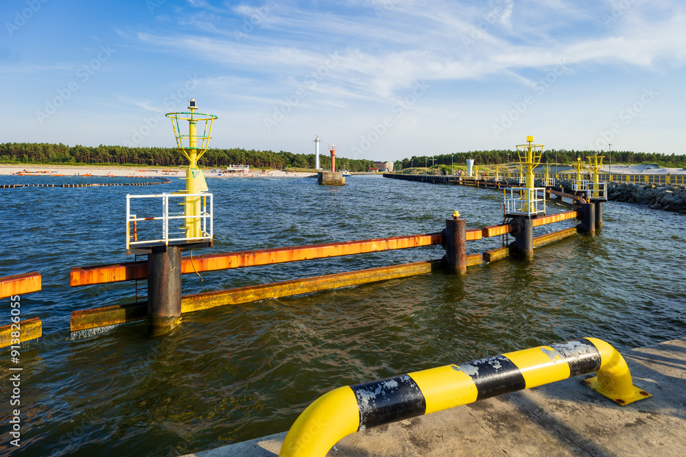 Entrance to the seaport. View of the forest beach and port from the breakwater. Bumpers in the foreground. Summer, Leba, Poland