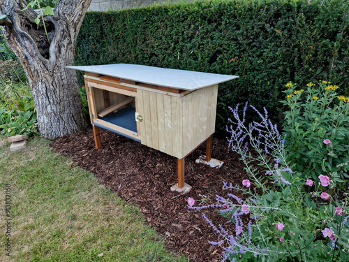 the home zoo is located on the edge of the flowerbed in a wooden shed with a screened gate against marten predators. guinea pigs or rabbits live here. lined with wood photo