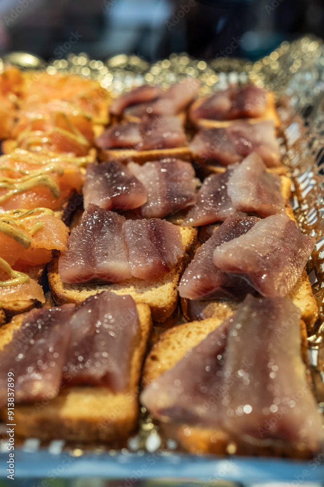 Delicious anchovies from the Cantabrian Sea on bread for sale at the counter of a grocery store in a food market. Delicious anchovies from the Cantabrian Sea on bread for sale at the counter of a grocery store in a food market.