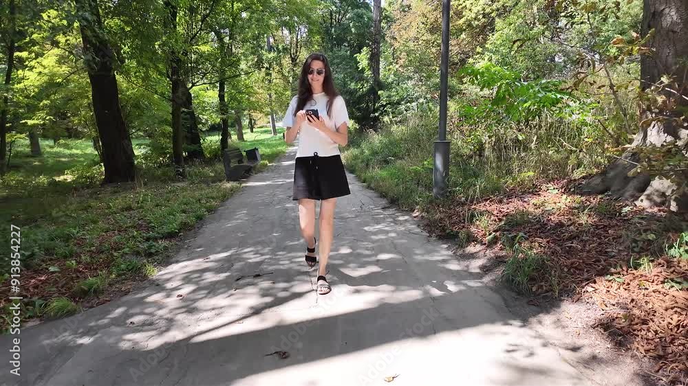 Woman walking in the city park on a sunny summer day with a tote bag Woman walking in the city park on a sunny summer day with a tote bag