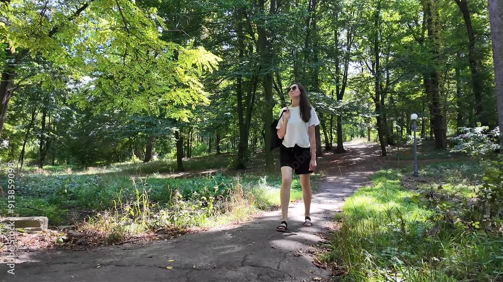Woman walking in the city park on a sunny summer day with a tote bag Woman walking in the city park on a sunny summer day with a tote bag