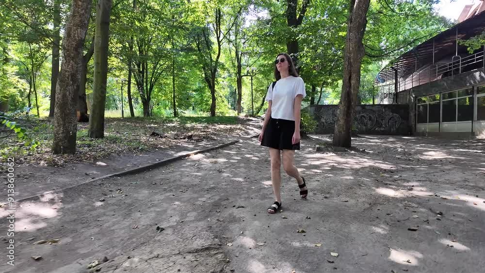 Woman walking in the city park on a sunny summer day with a tote bag Woman walking in the city park on a sunny summer day with a tote bag