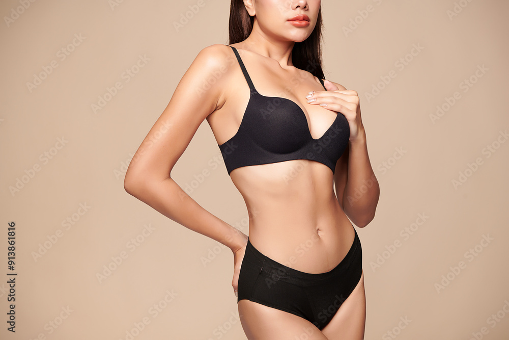 Naklejka premium Confident beautiful young asian woman posing in black lingerie on beige background, Perfect body,