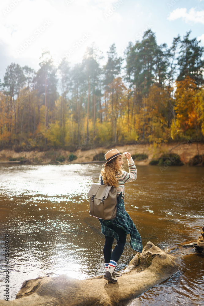 Happy woman traveler with backpack enjoying autumn hiking along the river. Active lifestyle. The concept of hiking, travel, vacation. Happy woman traveler with backpack enjoying autumn hiking along the river. Active lifestyle. The concept of hiking, travel, vacation.