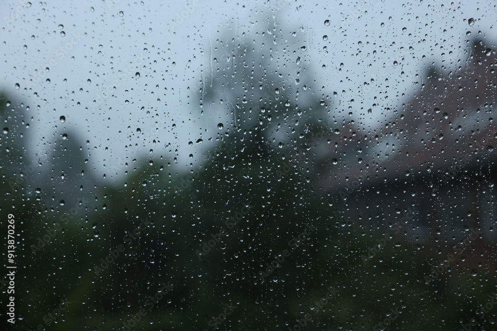 View on buildings through window with water droplets on rainy day, closeup View on buildings through window with water droplets on rainy day, closeup