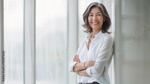 An elegant woman in a white blouse stands confidently in a bright, modern office with her arms crossed, smiling warmly at the camera. Free Download An elegant woman in a white blouse stands confidently in a bright, modern office with her arms crossed, smiling warmly at the camera. - GFXLoad