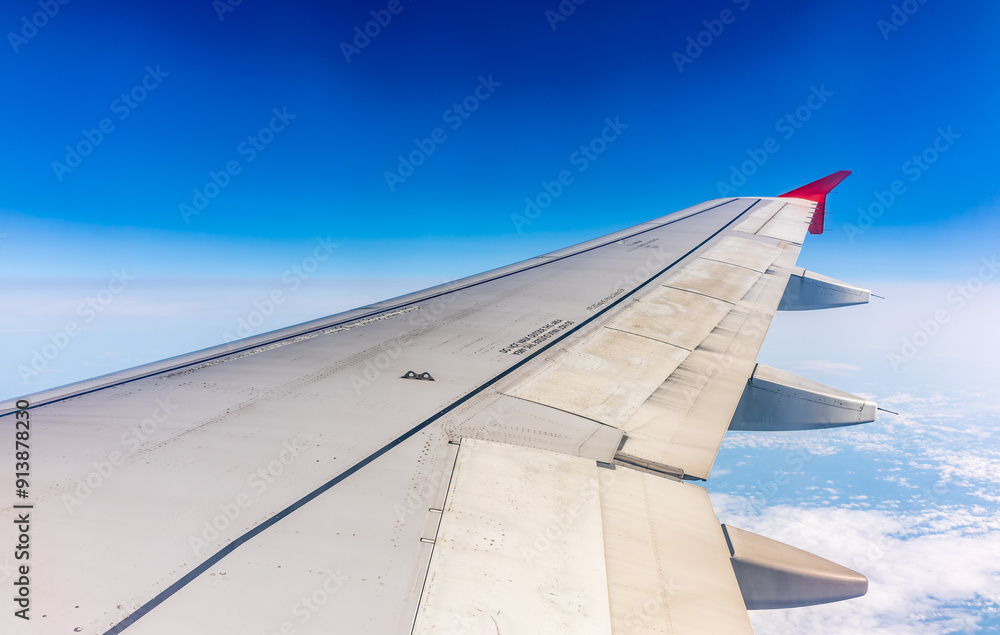 Fototapeta premium View from the airplane window at a beautiful cloudy sky and the airplane wing