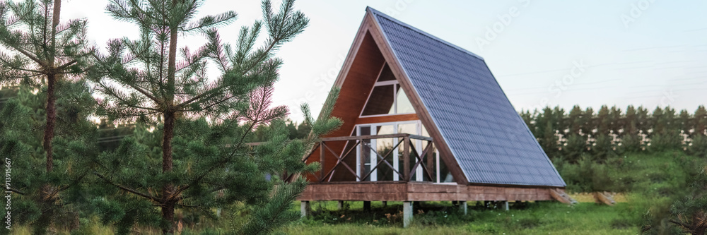 The concept of glamping and renting a chalet for weekend. Wooden house with a veranda in nature around coniferous trees The concept of glamping and renting a chalet for weekend. Wooden house with a veranda in nature around coniferous trees