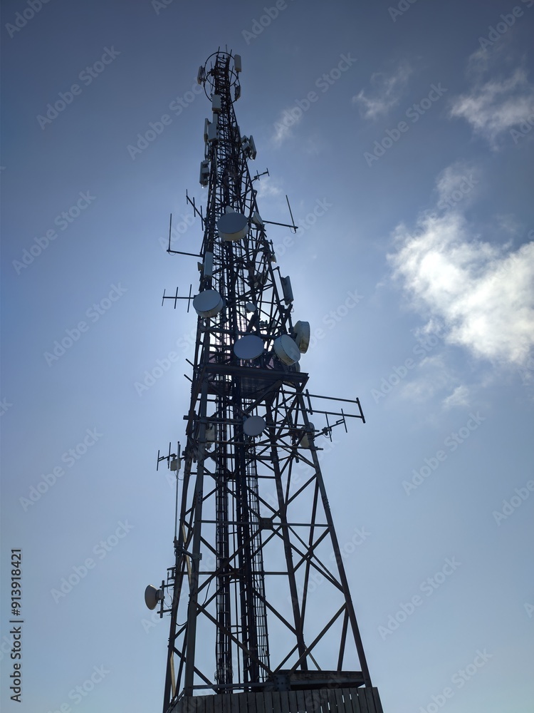 A tall telecommunication tower is strikingly visible with a clear sky as the background A tall telecommunication tower is strikingly visible with a clear sky as the background