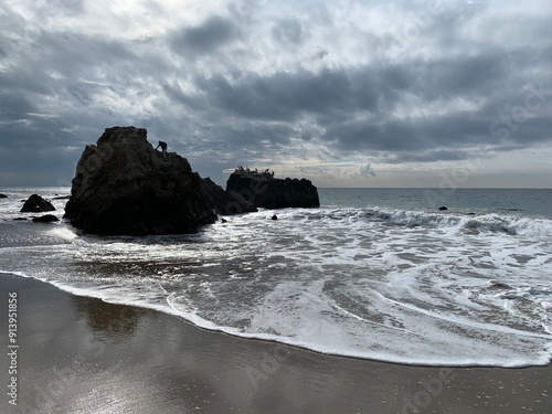 tide rolling in on the beach rocks rising out of the surf  photo