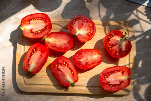 cherry tomatoes cut in hald on a wooden cutting board on a marble kitchen counter in the morning sunlight photo