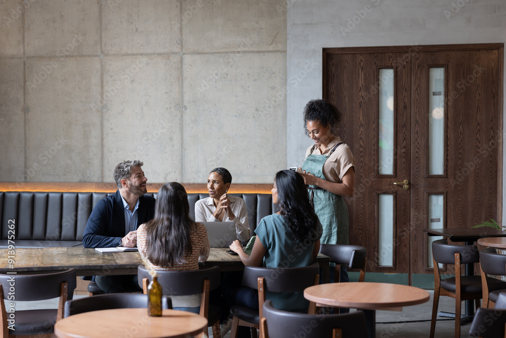 Waitress in a restaurant serving a group of businesspeople Waitress in a restaurant serving a group of businesspeople