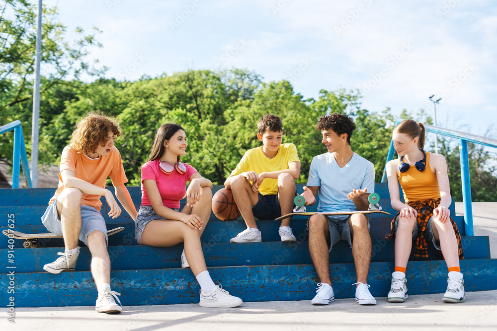 Smiling teenage friends with skateboard, talking together and sitting on stairs Smiling teenage friends with skateboard, talking together and sitting on stairs