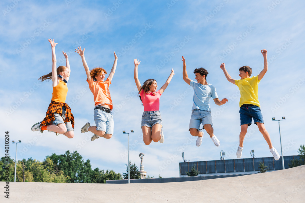 Naklejka premium Group of multiracial overjoyed friends, happy teenagers jumping high, having fun