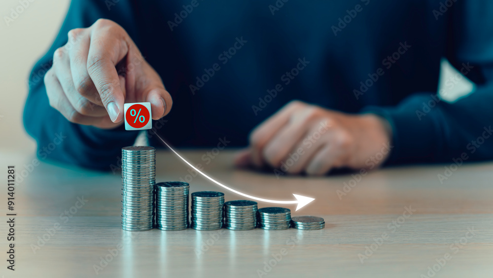 Percent sign moving down from top on coin stack. Central banking system cut interest rate, rising or lowering Fed interest rates to correct inflation concepts.