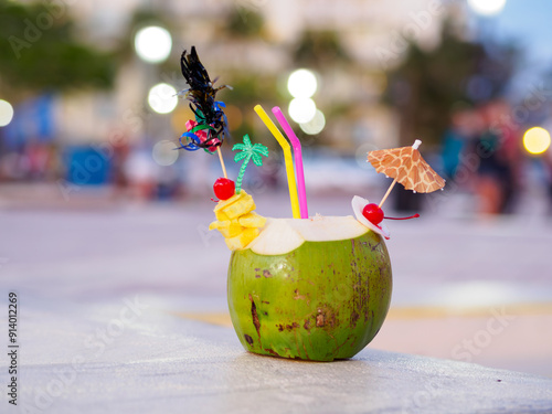 Coconut juice with straw and extras against blurred city background