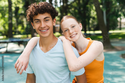 Portrait of attractive red hair girl embracing her male friend outdoors