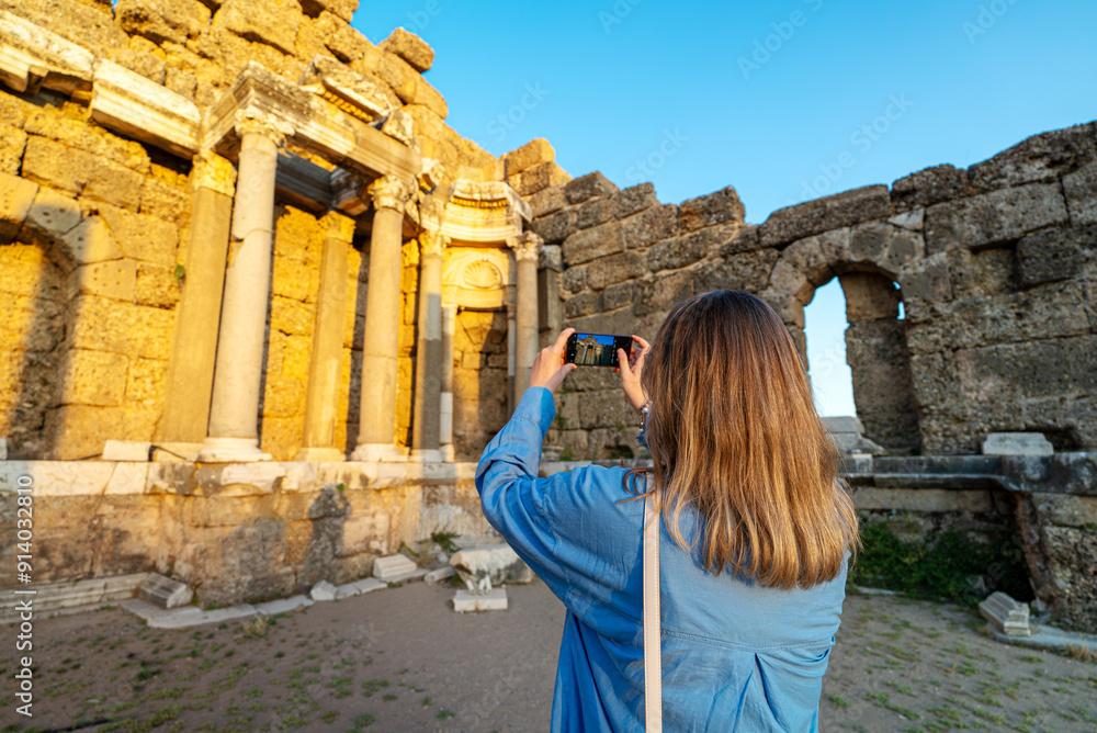 Fototapeta premium Female tourist takes a photo of the ruins of an ancient city.