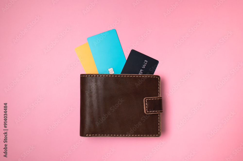 Brown leather wallet with colored plastic debit and credit bank cards on pink background, top view flat lay. Minimalistic concept of shopping, online payment. Stylish unisex wallet Brown leather wallet with colored plastic debit and credit bank cards on pink background, top view flat lay. Minimalistic concept of shopping, online payment. Stylish unisex wallet