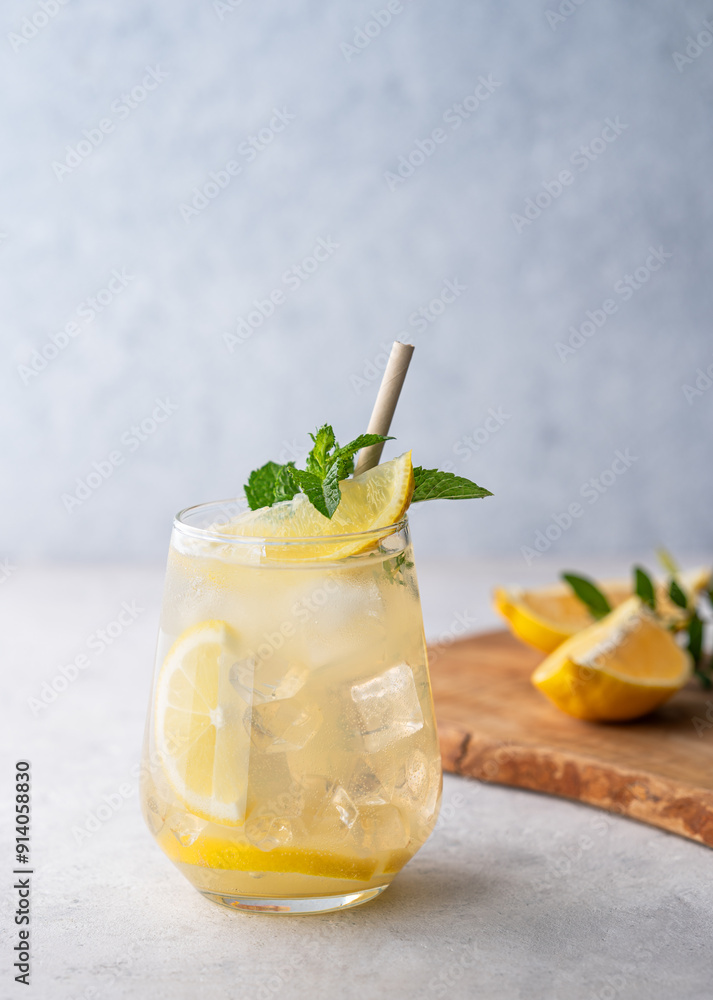 Fototapeta premium Mojito cocktail with fresh lemon, mint and ice. Refreshing citrus lemonade drink on a light background with wooden board.