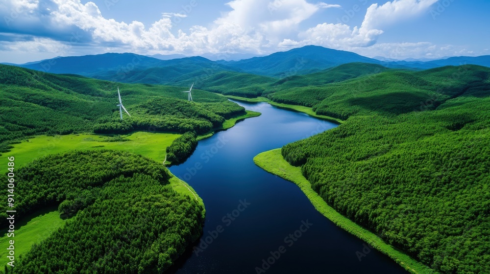 Fototapeta premium Aerial view of a serene river flowing through lush green mountains under a blue sky, showcasing nature's beauty and tranquility.