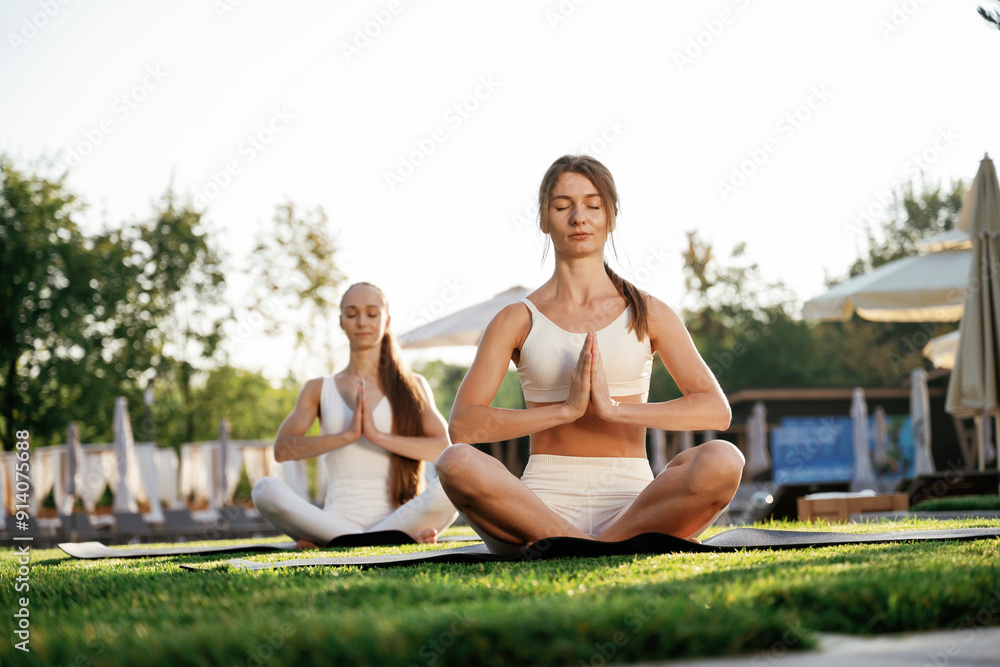 Meditation practice in lotus pose. Two fitness women are together outdoors, conception of sport