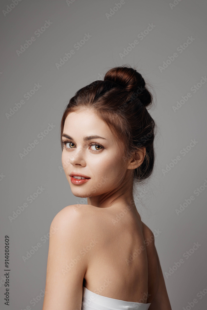 Beautiful young woman in a white dress posing for the camera on a gray background Beautiful young woman in a white dress posing for the camera on a gray background