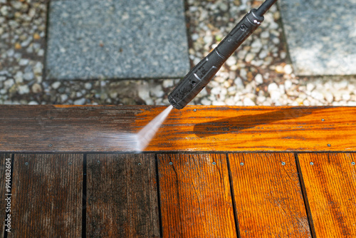 cleaning terrace with a power washer - high water pressure cleaner on wooden terrace surface