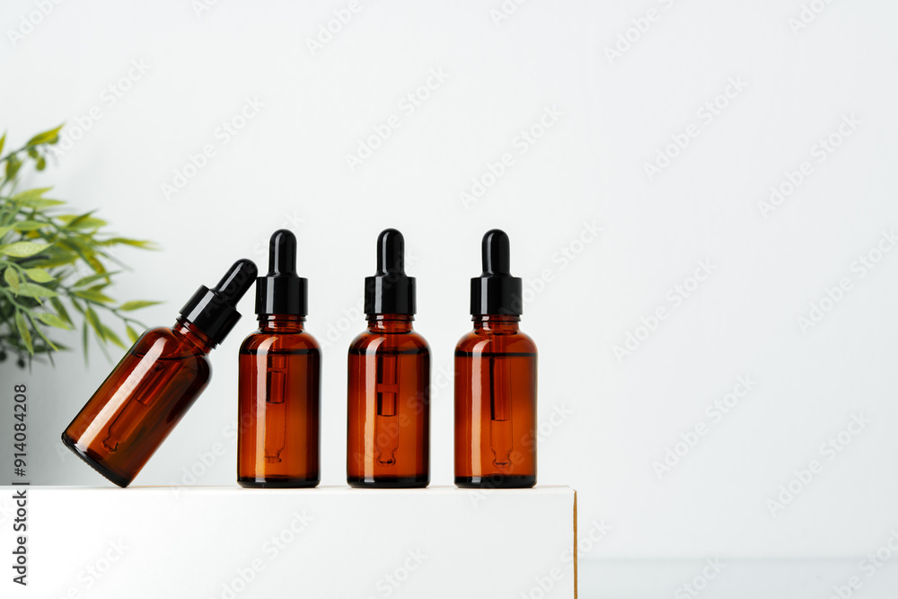 Four Amber Glass Dropper Bottles on White Surface Four Amber Glass Dropper Bottles on White Surface