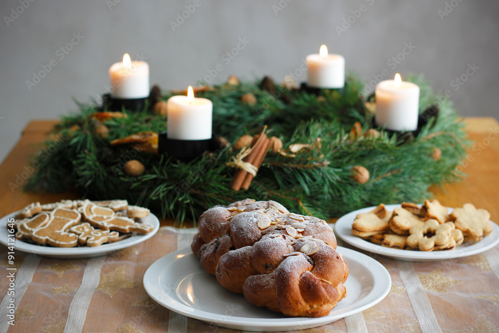 Traditional Czech and Slovak Christmas sweet plaited bread called vanocka (in Slovak vianocka). Christmas pastry on a festively set table, an advent wreath with four burning candles in the background. Traditional Czech and Slovak Christmas sweet plaited bread called vanocka (in Slovak vianocka). Christmas pastry on a festively set table, an advent wreath with four burning candles in the background.