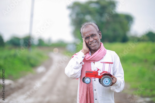 Indian farmer, equipped with a miniature tractor toy photo