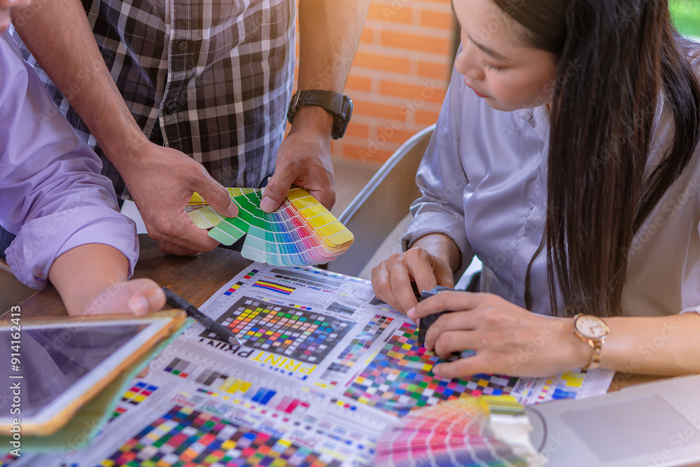 Worker checking print quality of media graphics proof print and color tone in printing industry. Selected focus Worker checking print quality of media graphics proof print and color tone in printing industry. Selected focus