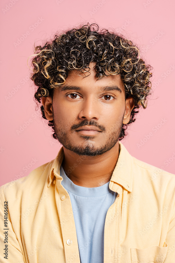 Portrait of Indian adult male with curly hair posing on pink background Portrait of Indian adult male with curly hair posing on pink background