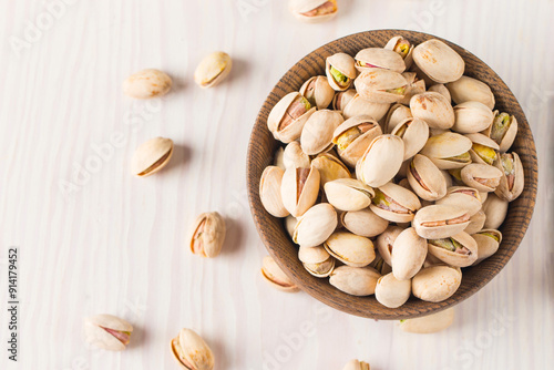 Organic roasted pistachio nuts in a wooden bowl. Top view. 