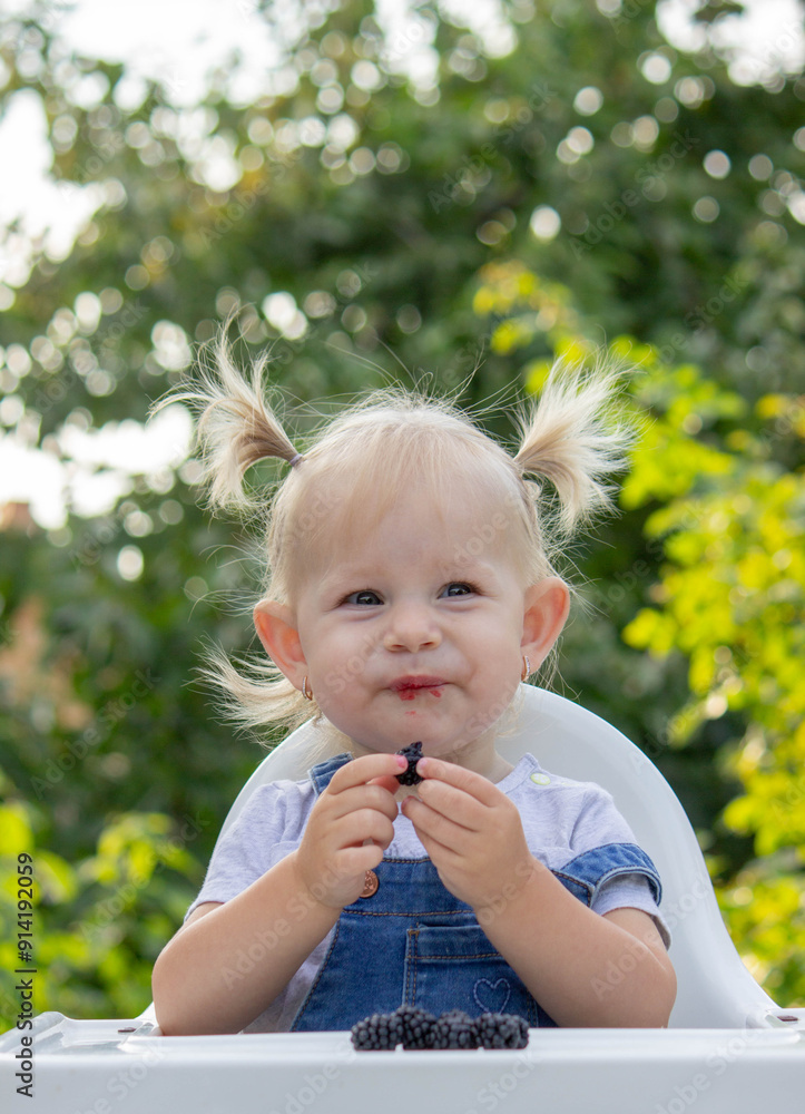 little happy girl eating blackberry. Selective focus little happy girl eating blackberry. Selective focus