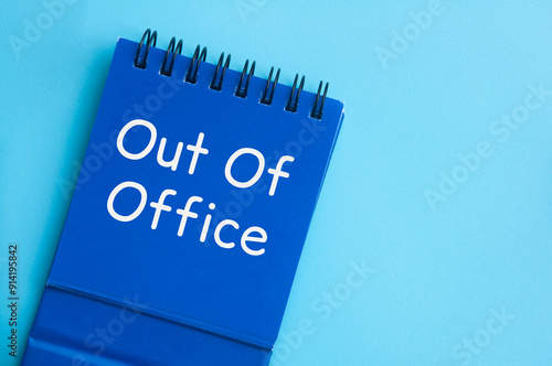 Top view of Out Of Office text on blue notepad. Vacation of annual leave concept photo