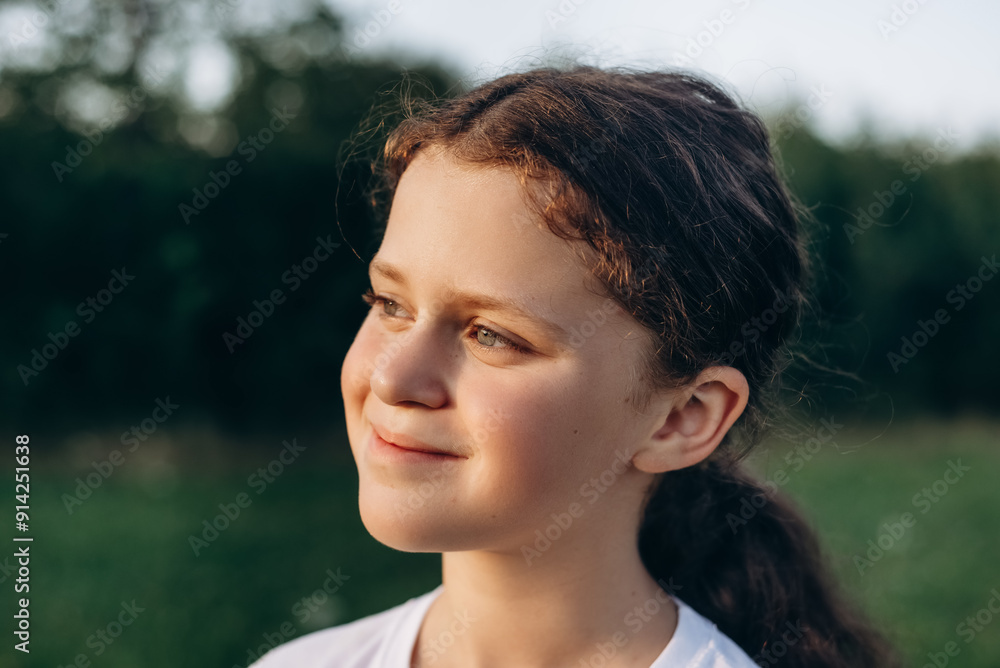 Portrait of smiling charming pretty little girl in park at summer warm day. Adorable happy child is dreaming looking at side on lawn outdoors. Children day. Childhood and nature concept Portrait of smiling charming pretty little girl in park at summer warm day. Adorable happy child is dreaming looking at side on lawn outdoors. Children day. Childhood and nature concept