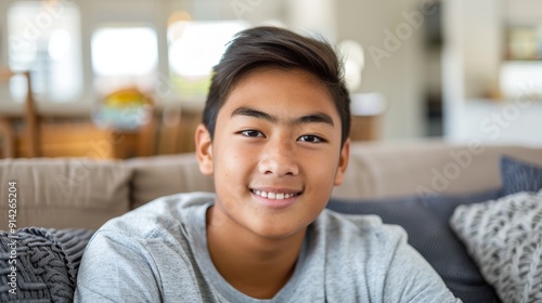 A serene teenage boy relaxes on a bright, modern sofa, enjoying a peaceful moment in his living room.