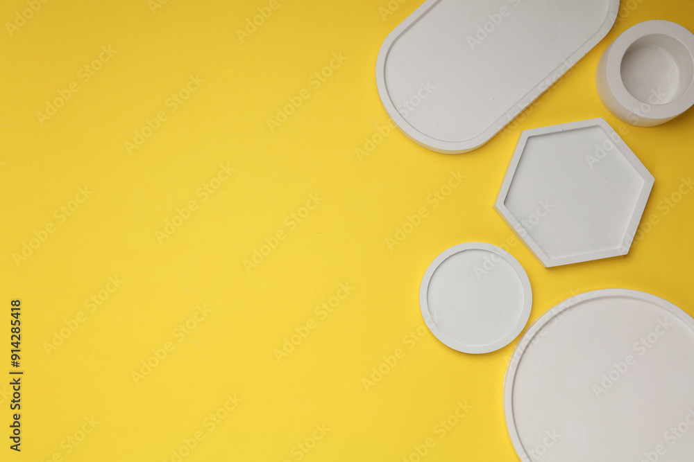 Set of Decorative white plaster trays of different shapes on yellow background. Stands for candles organizers for cosmetics or jewelry. Set of Decorative white plaster trays of different shapes on yellow background. Stands for candles organizers for cosmetics or jewelry.