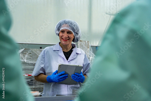 caucasion woman working in a food factory wearing protective clothes and gloves.