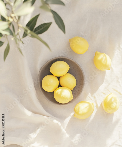 Wallpaper Mural Ceramic platter with fresh ripe lemons on table covered with light linen tablecloth with shade from olive branches. Top view. An unleavened light still life of a sunny day in southern Italy. Pure. Torontodigital.ca