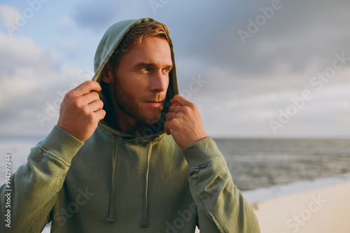 Close up young strong sporty fit sportsman man wear grey sports casual clothes hold hood look aside warm up training at sunrise sun dawn over sea beach outdoor on pier seaside in summer day morning. photo