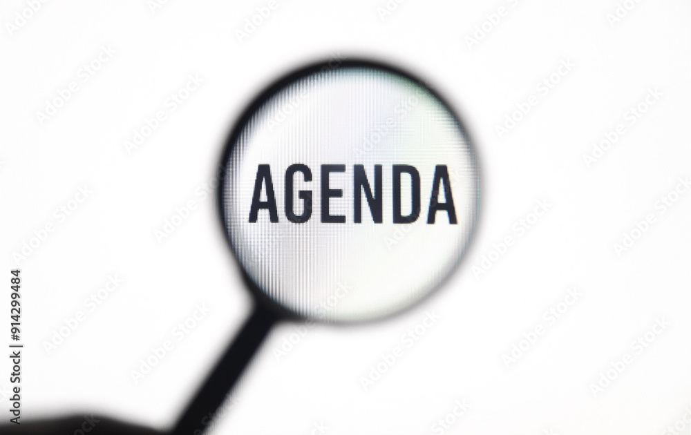 Word agenda on screen through magnifying glass close-up Word agenda on screen through magnifying glass close-up