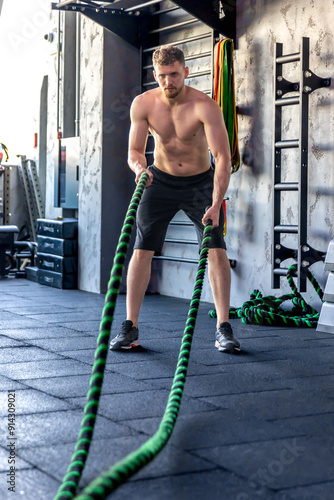 Ahlete performs triceps exercises with cross fit rope. Sports lifestyle. photo