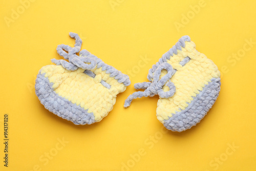 Knitted shoes for a newborn on a yellow background photo