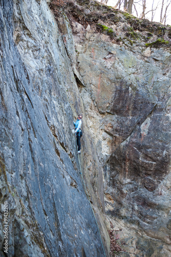 rock climber climbs an almost vertical wall of rock with a safety rope