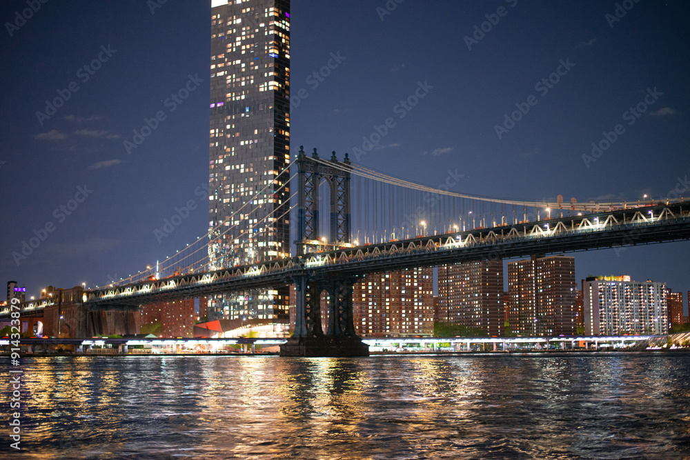 Fototapeta premium night view of manhattan behind the lace farms of manhattan bridge across east river 