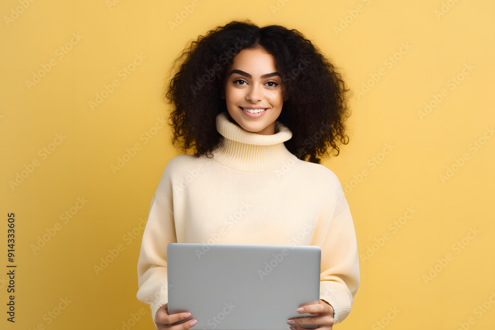 woman with curly hair holding laptop looking into the camera over yellow background woman with curly hair holding laptop looking into the camera over yellow background